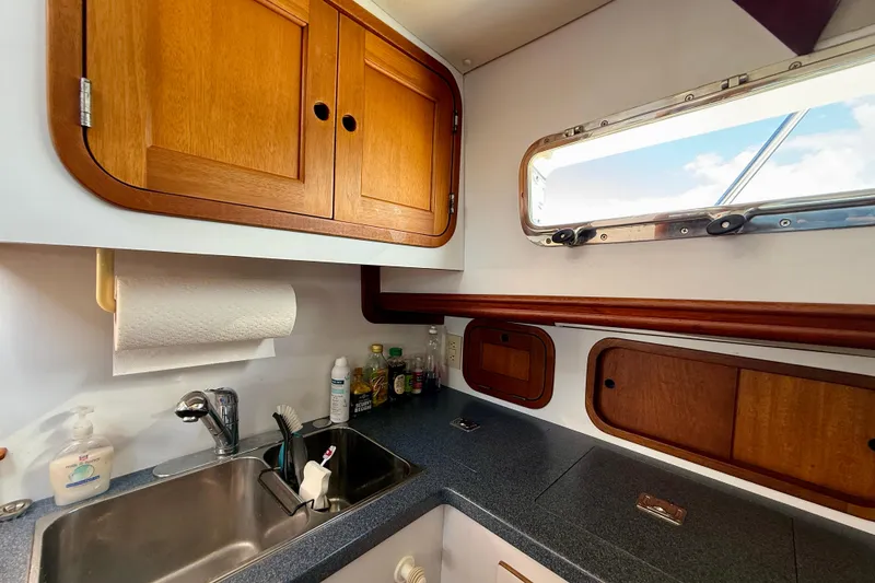 Slide: The Image of 1999 Legacy 40 yacht kitchen with wooden cabinets, sink, and window view. - 29