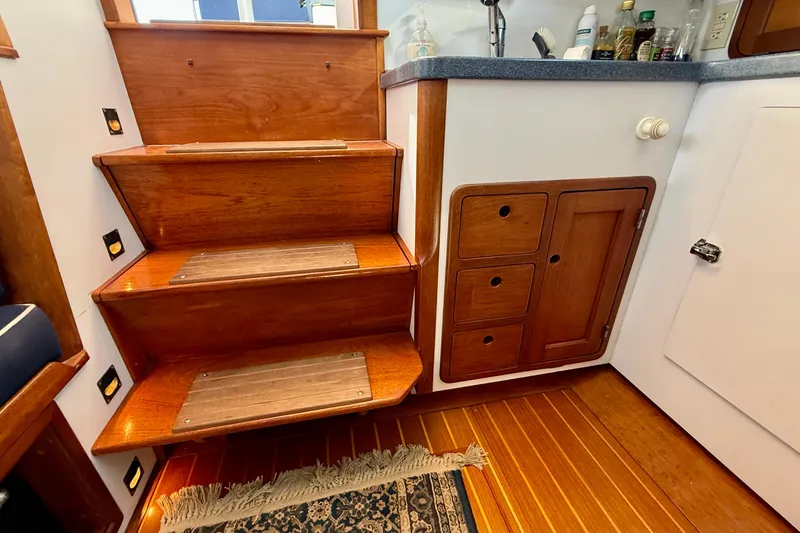 Slide: The Image of Wooden stairs and cabinetry inside a 1999 Legacy 40 boat, featuring a small kitchenette. - 30