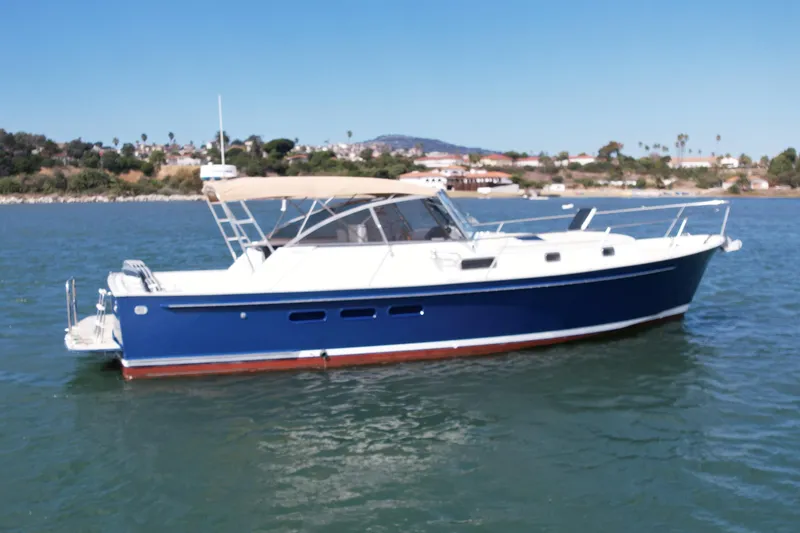 Slide: The Image of 1999 Legacy 40 boat with blue hull cruising on a sunny day near the shore. - 4