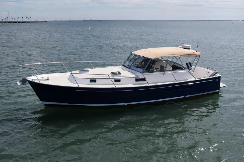 Slide: The Image of 1999 Legacy 40 boat with blue hull and beige canopy on calm water. - 5