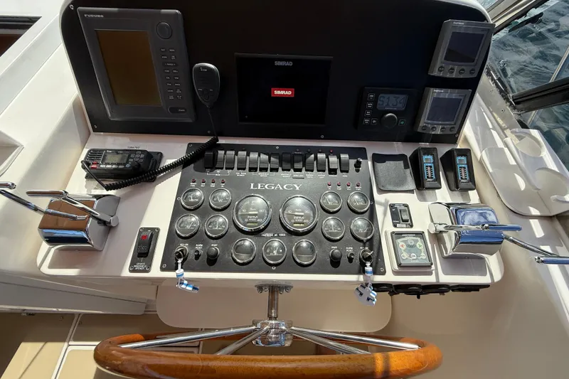 Slide: The Image of Control panel of a 1999 Legacy 40 boat with navigation instruments and steering wheel. - 57