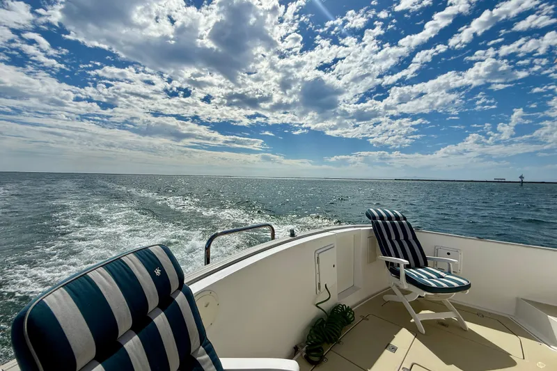 Slide: The Image of Legacy 40 yacht deck with striped chairs, ocean view, and blue sky, 1999 model. - 67