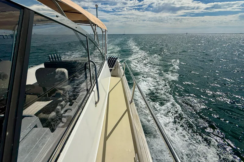 Slide: The Image of Legacy 40 boat cruising on open sea, leaving a wake behind, under a partly cloudy sky. - 73