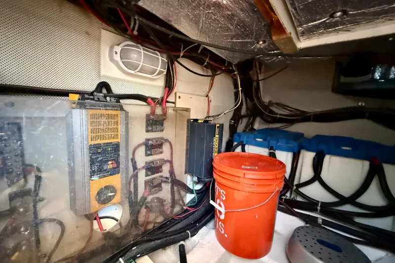 Slide: The Image of Electrical system inside a 1999 Legacy 40 boat, featuring wiring, equipment, and an orange bucket. - 78