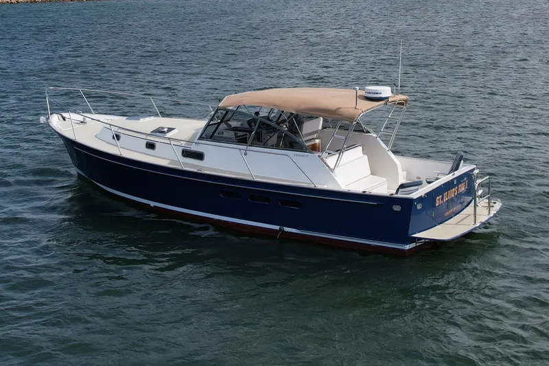 Slide: The Image of 1999 Legacy 40 boat with blue hull and tan canopy on open water. - 8