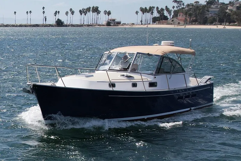 Slide: The Image of 1999 Legacy 40 boat cruising on ocean near palm-lined shore. - 9