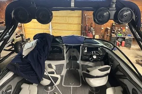 Slide: The Image of 2016 Monterey 238 Surf boat interior with speakers and seating in a garage setting. - 2