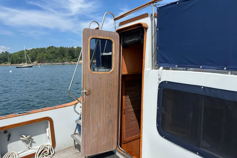 Slide: The Image of 1987 Albin North Sea Trawler with open cabin door, docked near scenic shoreline. - 10