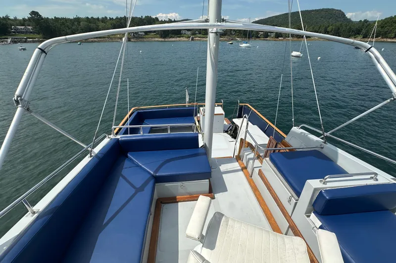 Slide: The Image of 1987 Albin North Sea Trawler with blue seating, docked in a scenic bay. - 23