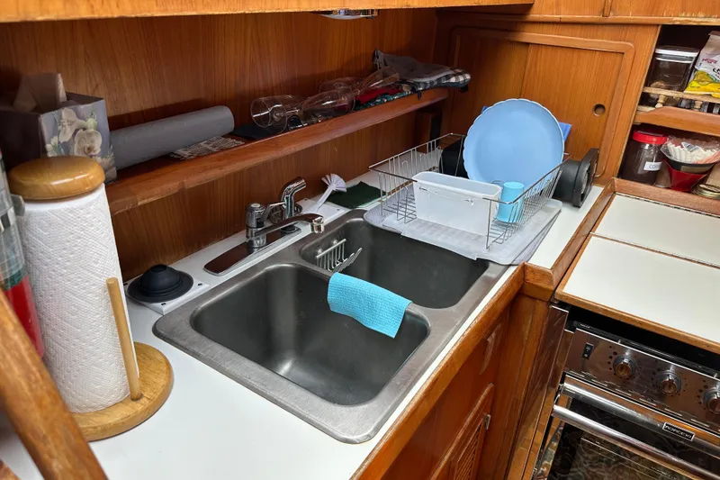 Slide: The Image of 1987 Albin North Sea Trawler kitchen with sink, dish rack, and wooden cabinetry. - 65