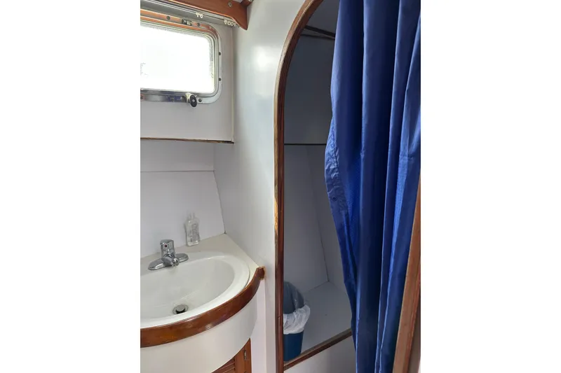 Slide: The Image of 1987 Albin North Sea Trawler bathroom with sink, window, and blue shower curtain. - 73