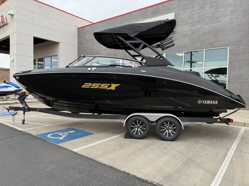 Slide: The Image of 2025 Yamaha Boats 255XD in black on a trailer, parked outside a building. - 2