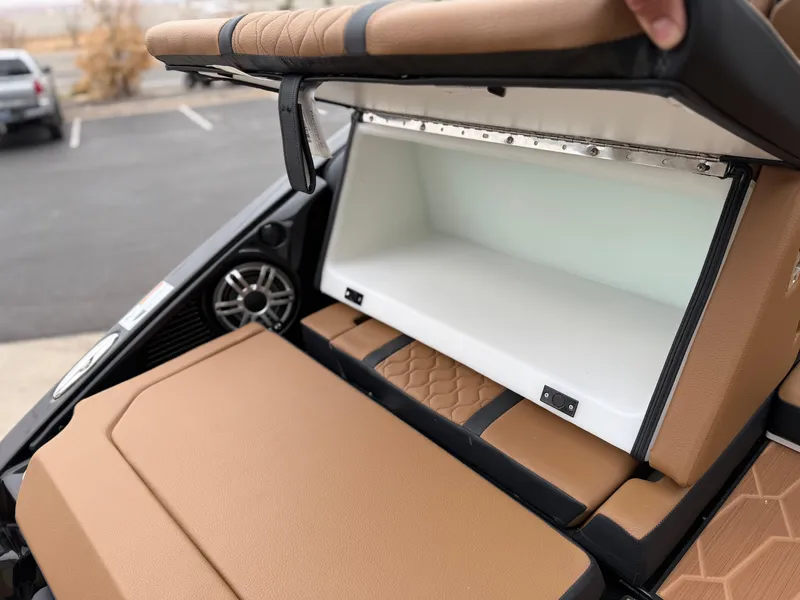 Slide: The Image of 2025 Yamaha Boats 255XD storage compartment with tan seating and speaker detail. - 20
