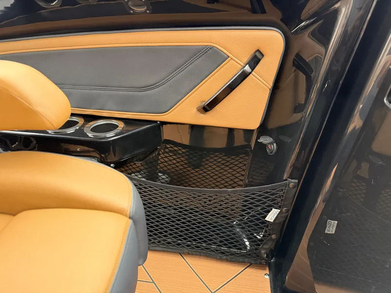 Slide: The Image of 2025 Yamaha Boats 255XD interior with tan and black seating, cup holders, and storage net. - 31