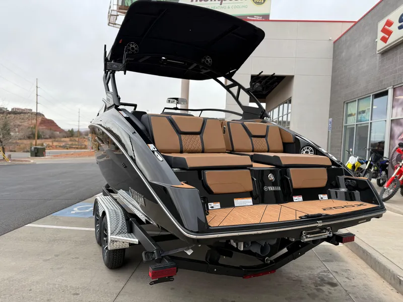 Slide: The Image of 2025 Yamaha Boats 255XD, sleek black design, parked on trailer outside dealership. - 4