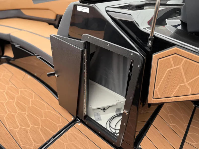 Slide: The Image of 2025 Yamaha Boats 255XD interior storage compartment with sleek design and wood accents. - 56