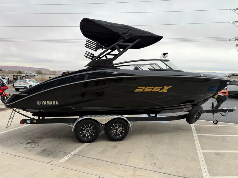 Slide: The Image of 2025 Yamaha Boats 255XD, sleek black design on a trailer, side view. - 8