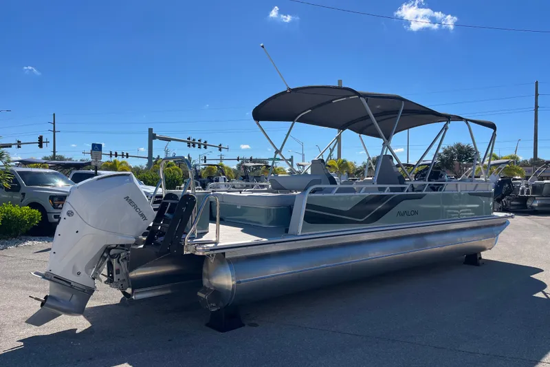 Slide: The Image of 2026 Avalon 2585 Venture 85 VRB Tri Toon boat with Mercury engine, parked outdoors. - 5