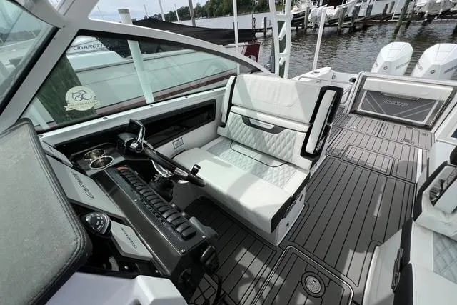 Slide: The Image of 2023 Blackfin 272 DC boat interior with modern helm and seating, docked at marina. - 9