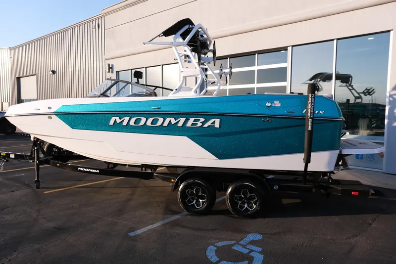 Slide: The Image of 2026 Moomba Max boat in teal and white, parked outside a building. - 3