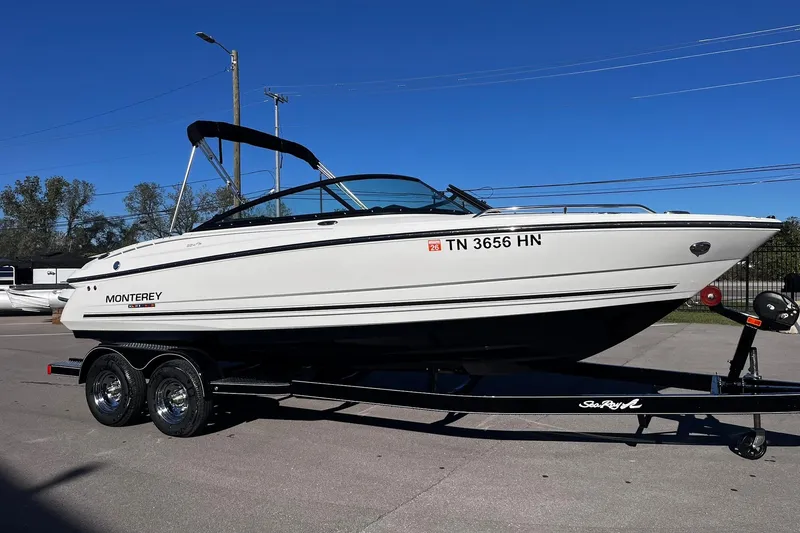 Slide: The Image of 2022 Monterey 224FS boat on trailer, parked outdoors under clear blue sky. - 0