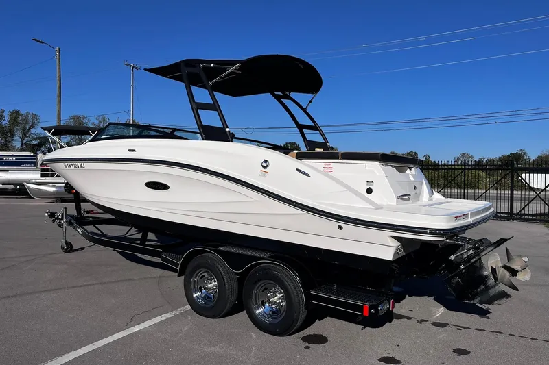 Slide: The Image of 2024 Sea Ray SPX 230 boat on trailer, parked outdoors under clear blue sky. - 2