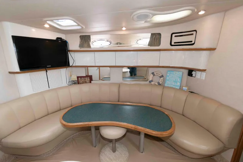 Slide: The Image of Interior of 1995 Sea Ray 440 Sundancer yacht with curved seating and mounted TV. - 10