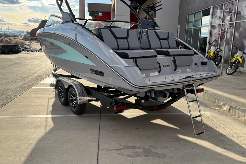 Slide: The Image of 2026 Yamaha Boats 255XD on trailer, sleek design, gray exterior, docked outdoors. - 10