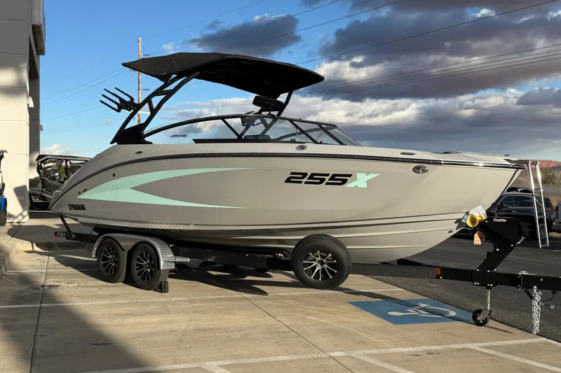 Slide: The Image of 2026 Yamaha Boats 255XD on trailer, sleek design, parked outdoors under cloudy sky. - 5