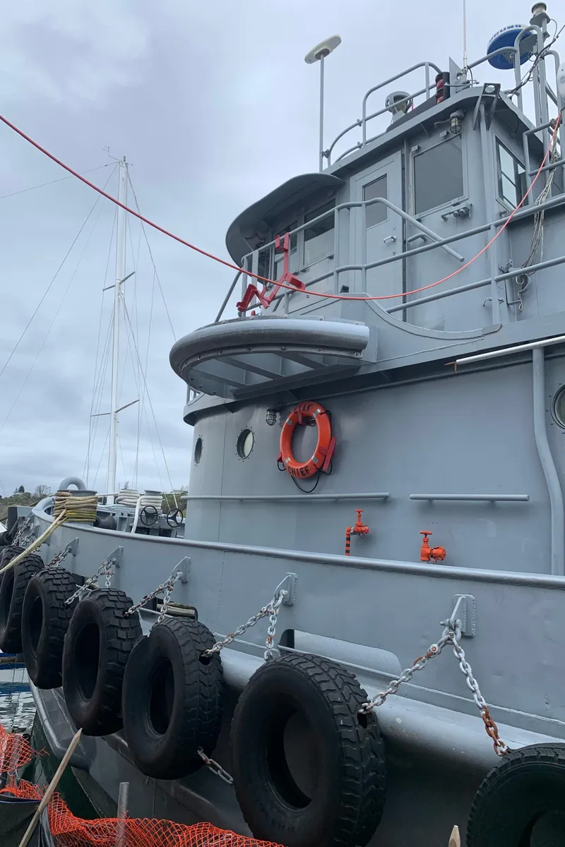 Slide: The Image of 1955 L-T 100 Steel Army Tugboat docked, featuring life preserver and tires for protection. - 41