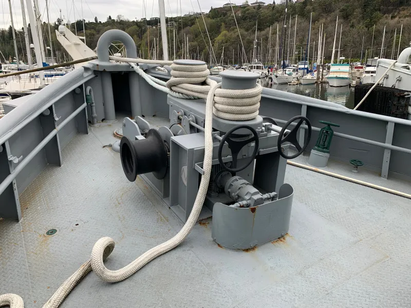 Slide: The Image of 1955 L-T 100 Steel Army Tugboat deck with ropes and winch, docked in a marina. - 5