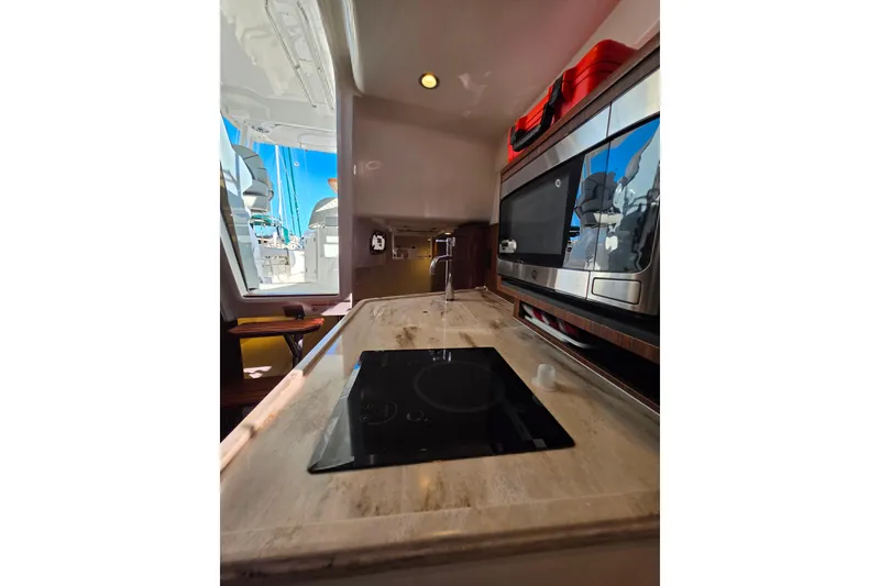 Slide: The Image of 2024 Pursuit OS 325 Offshore boat storage compartment with coiled hose and seating. - 31