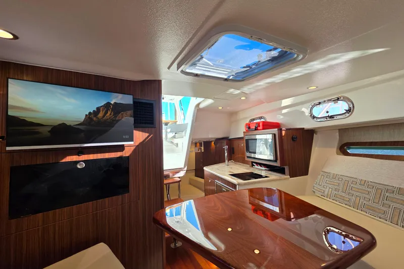 Slide: The Image of 2024 Pursuit OS 325 Offshore boat interior with helm, seating, and table in marina setting. - 36