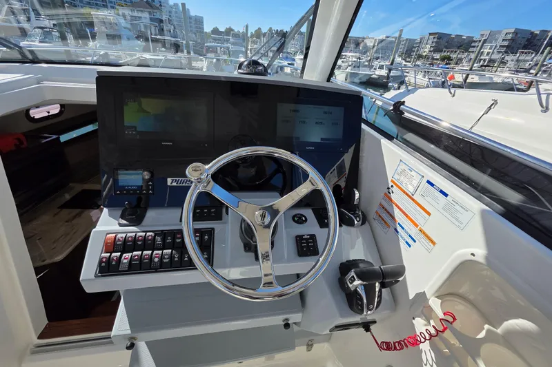 Slide: The Image of 2024 Pursuit OS 325 Offshore boat helm with advanced navigation controls and steering wheel. - 43