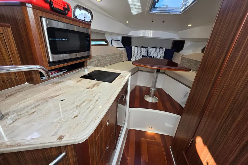 Slide: The Image of 2024 Pursuit OS 325 Offshore interior with kitchenette and seating area. - 53