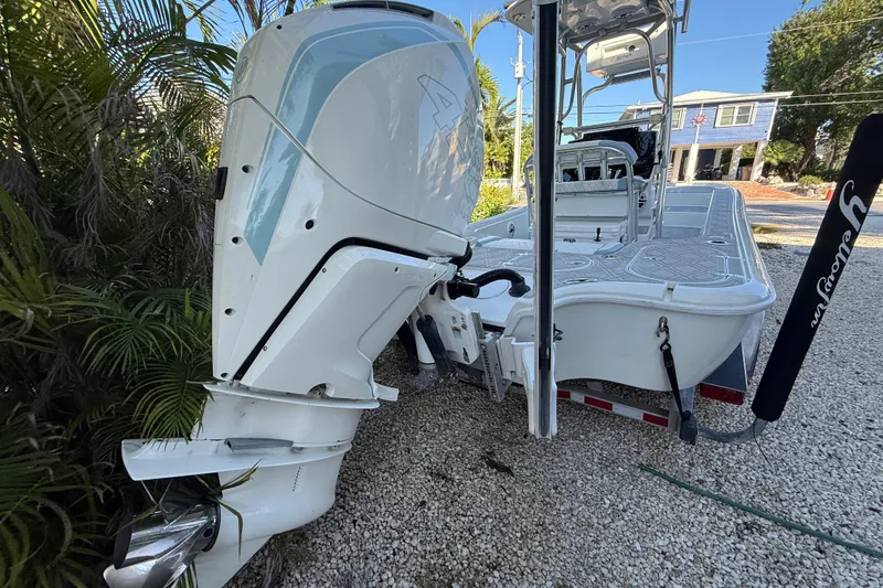 Slide: The Image of 2016 Yellowfin 24 Bay boat with outboard motor on trailer, parked on gravel. - 3