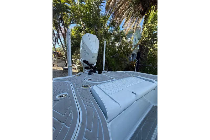 Slide: The Image of 2016 Yellowfin 24 Bay boat with sleek deck design and outboard motor, surrounded by tropical foliage. - 5