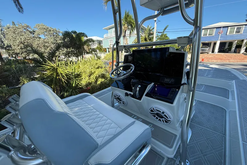 Slide: The Image of 2016 Yellowfin 24 Bay boat interior with steering console and seating, surrounded by tropical plants. - 6