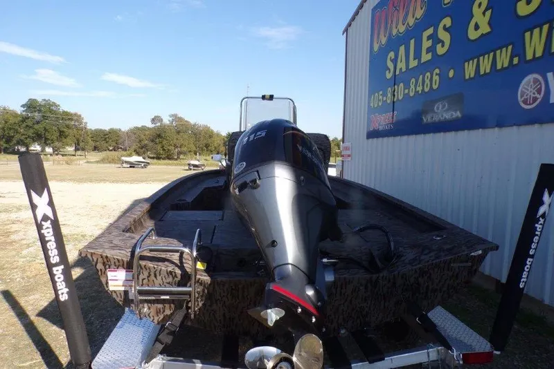 Slide: The Image of 2026 Xpress H20B Bay boat with motor, parked outside a sales building. - 1