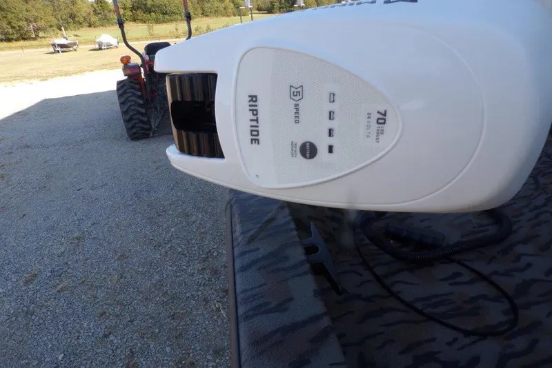 Slide: The Image of Riptide motor on 2026 Xpress H20B Bay boat, parked on gravel with tractor in background. - 16