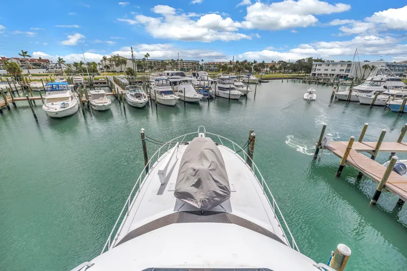 Slide: The Image of 1999 Viking 72 Enclosed Bridge yacht docked in a marina under a bright blue sky. - 104