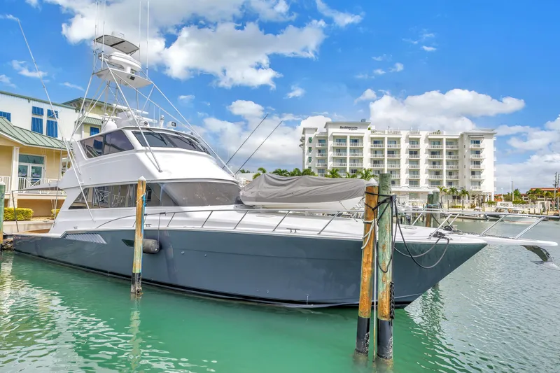 Slide: The Image of 1999 Viking 72 Enclosed Bridge yacht docked in marina, clear sky, modern buildings. - 11