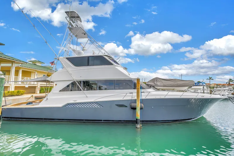 Slide: The Image of 1999 Viking 72 Enclosed Bridge yacht docked in a marina under a blue sky. - 13