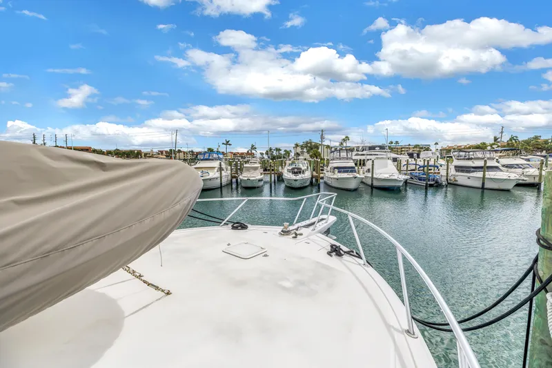 Slide: The Image of 1999 Viking 72 Enclosed Bridge yacht docked in a marina under a bright blue sky. - 15