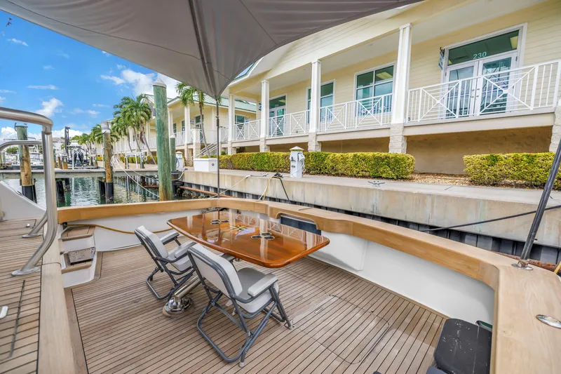 Slide: The Image of 1999 Viking 72 Enclosed Bridge yacht deck with seating, docked near waterfront buildings. - 26