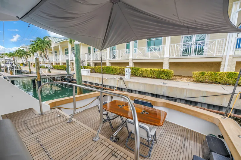 Slide: The Image of 1999 Viking 72 Enclosed Bridge yacht docked, featuring a shaded deck with seating. - 28