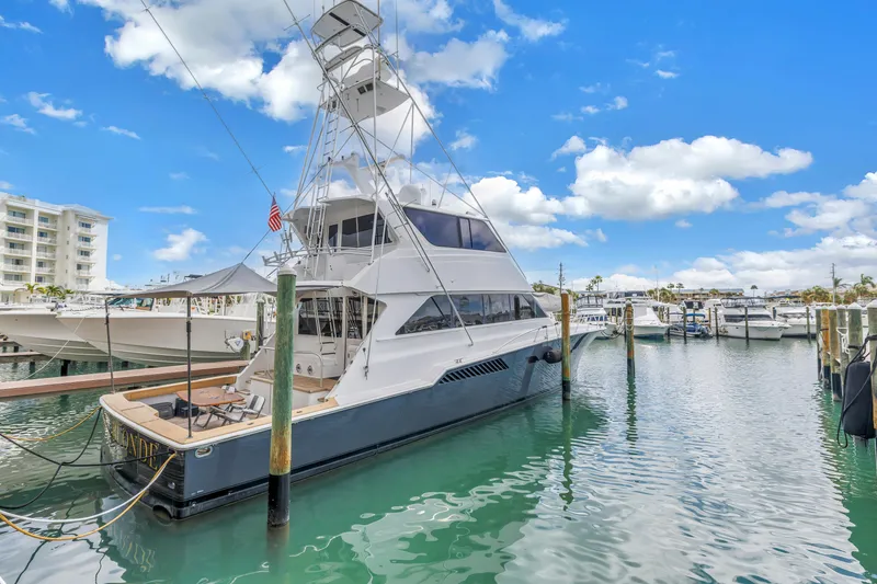 Slide: The Image of 1999 Viking 72 Enclosed Bridge yacht docked in a marina under a clear blue sky. - 4