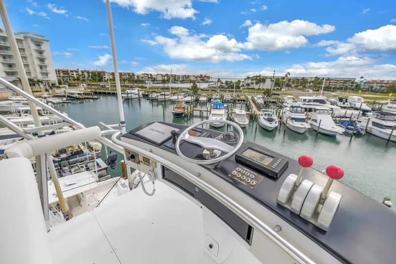 Slide: The Image of 1999 Viking 72 Enclosed Bridge yacht helm overlooking marina with boats and buildings. - 93