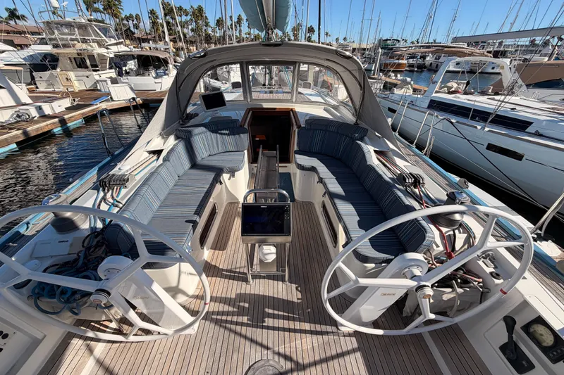 Slide: The Image of 2008 Hanse 540e sailboat cockpit with dual steering wheels and striped seating at marina. - 35
