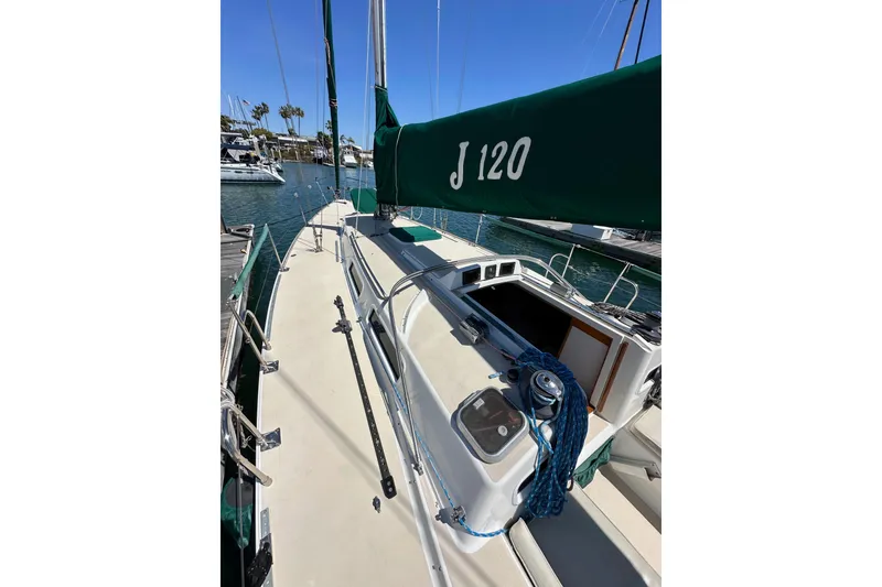 Slide: The Image of 1996 J Boats J/120 sailboat docked, featuring green sail cover and open hatch. - 10